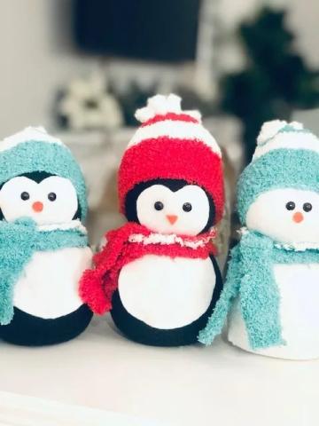 Two penguins and a snowman wearing red and blue hats and scarves.