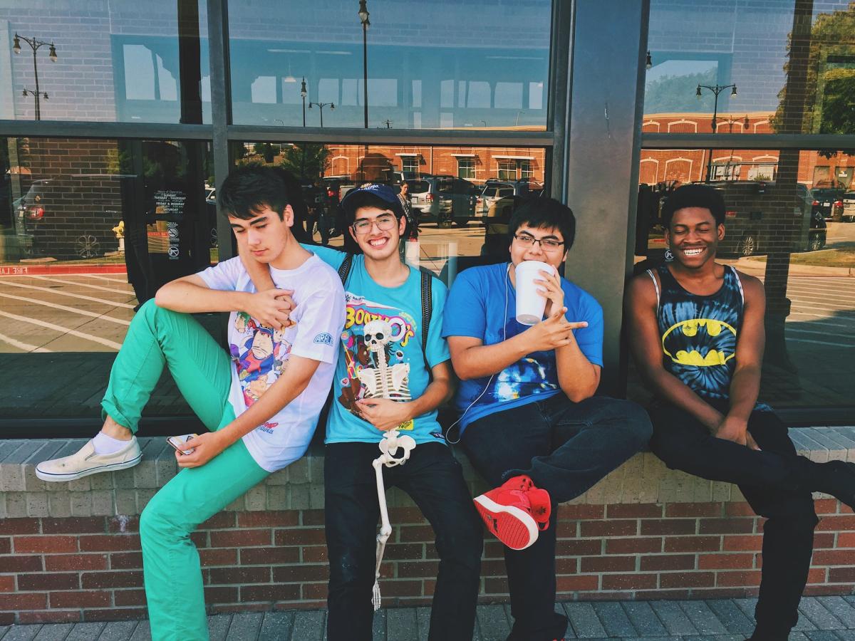 Four teens hanging out, outside a building.